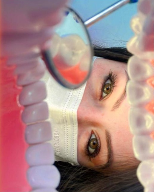 Dra. Carolina Ferreira observando um modelo de dentes pelo espelho clínico